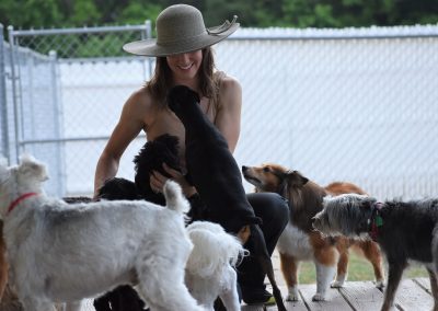 Dogs run up to greet woman at Smith Farms Kennel, the best kennel in Conyers, Georgia, providing Atlanta Doggy Daycare and Boarding